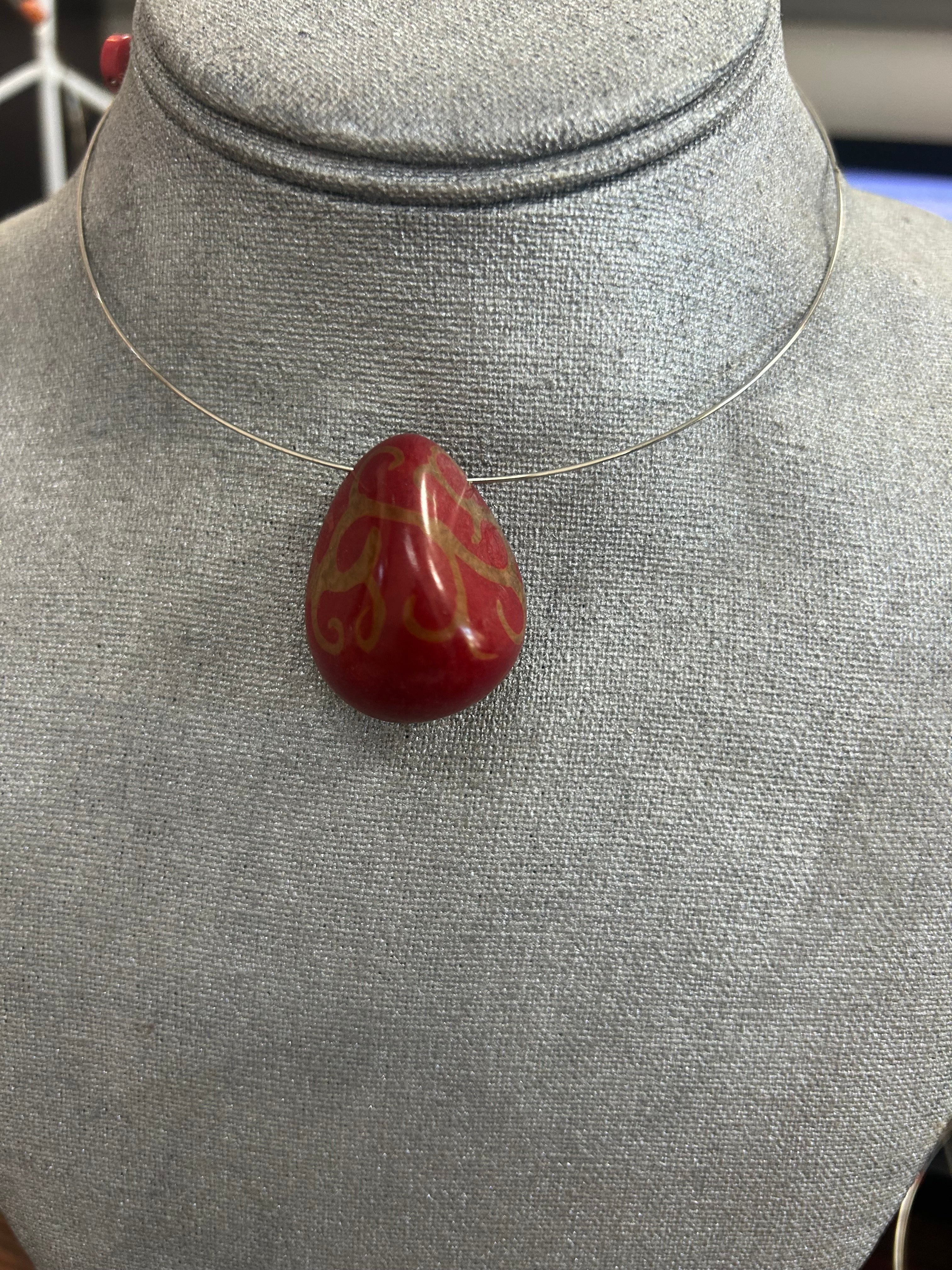 Collar con dije de piedra pulida en tono rojo intenso decorado con delicados detalles dorados