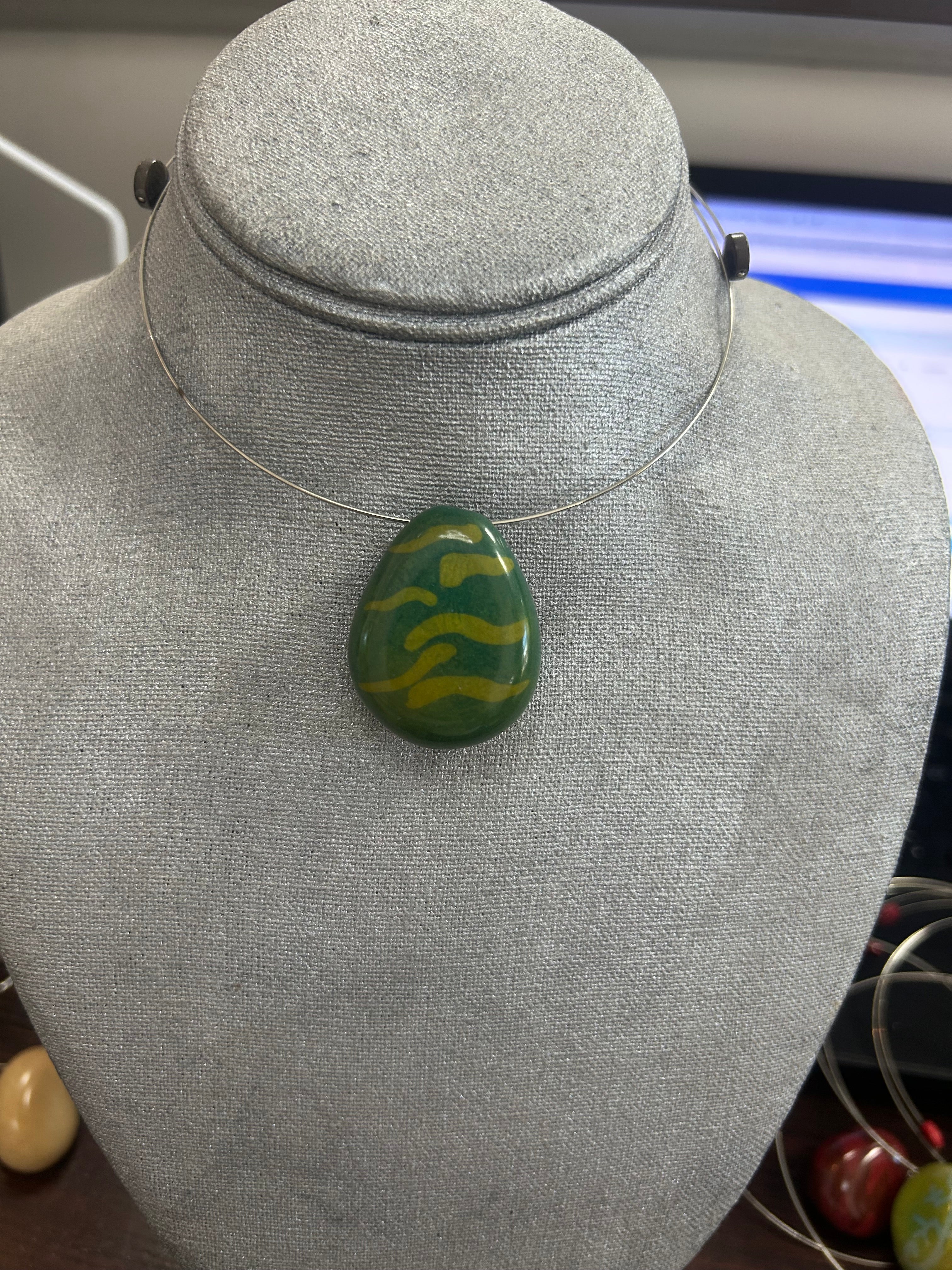 Collar con dije de piedra pulida en tono verde profundo con detalles ondulados en amarillo