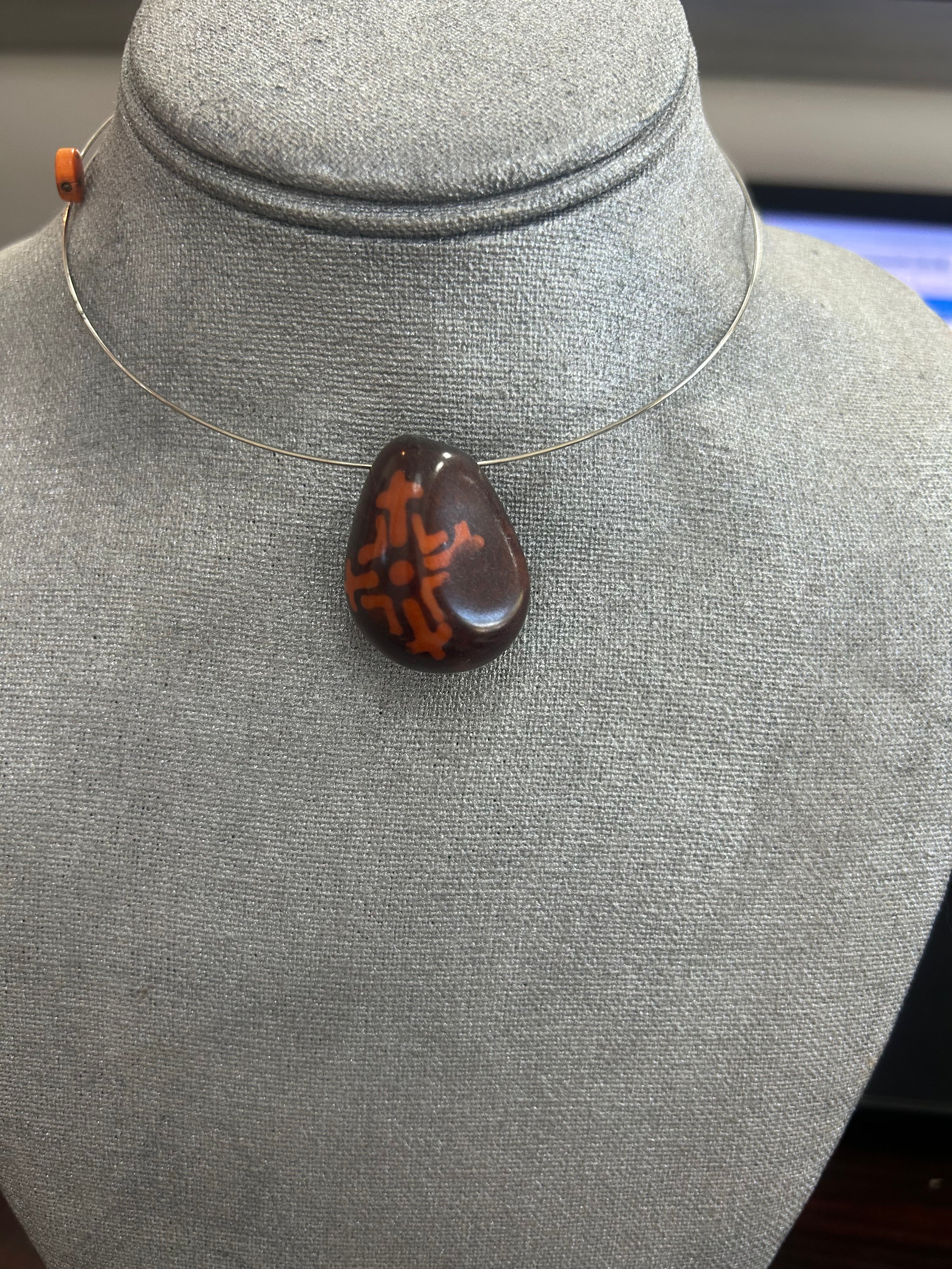 Collar con dije de piedra pulida en tono marrón oscuro, con diseño central en terracota
