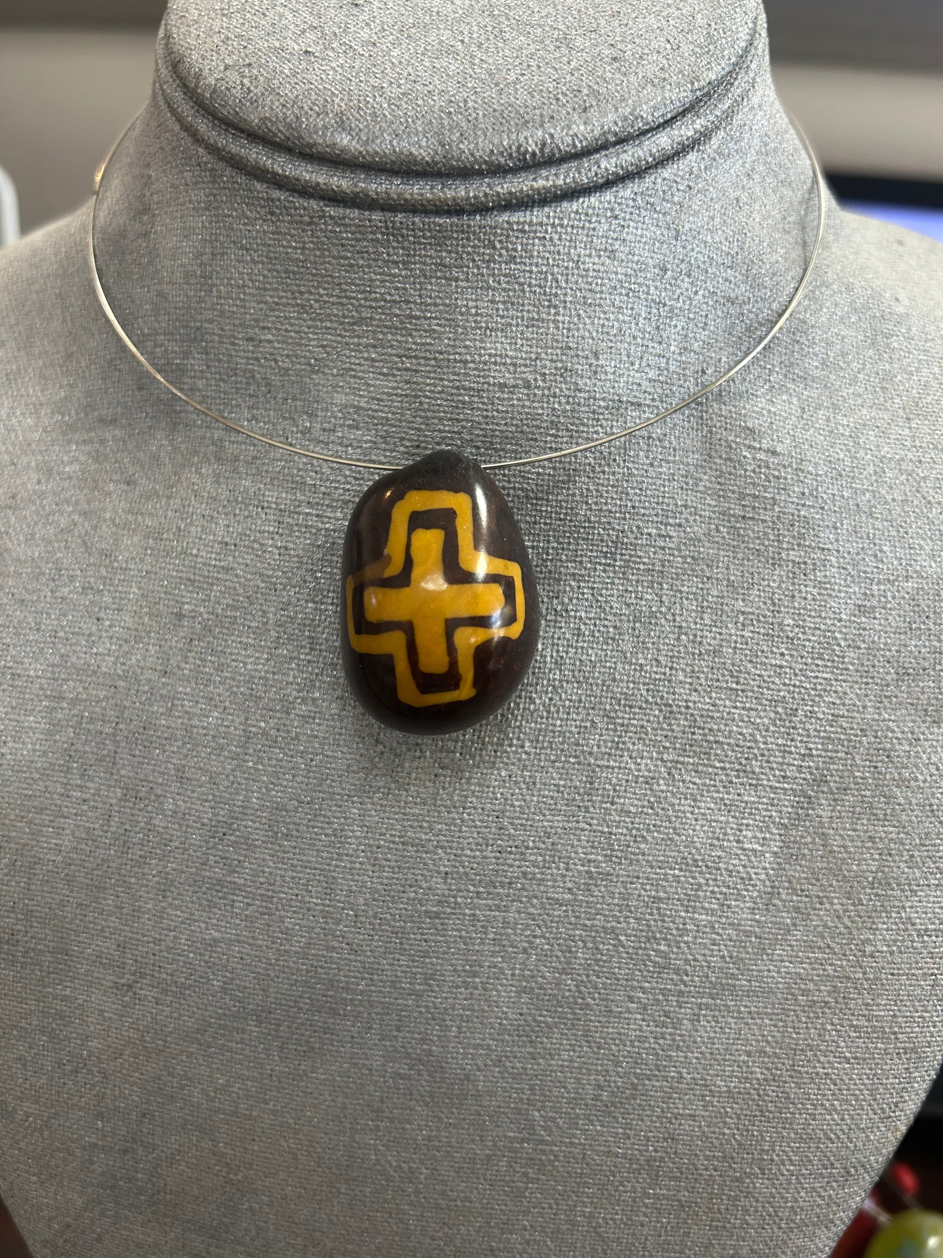 Collar con dije de piedra pulida en tono marrón oscuro con diseño central geométrico en amarillo mostaza