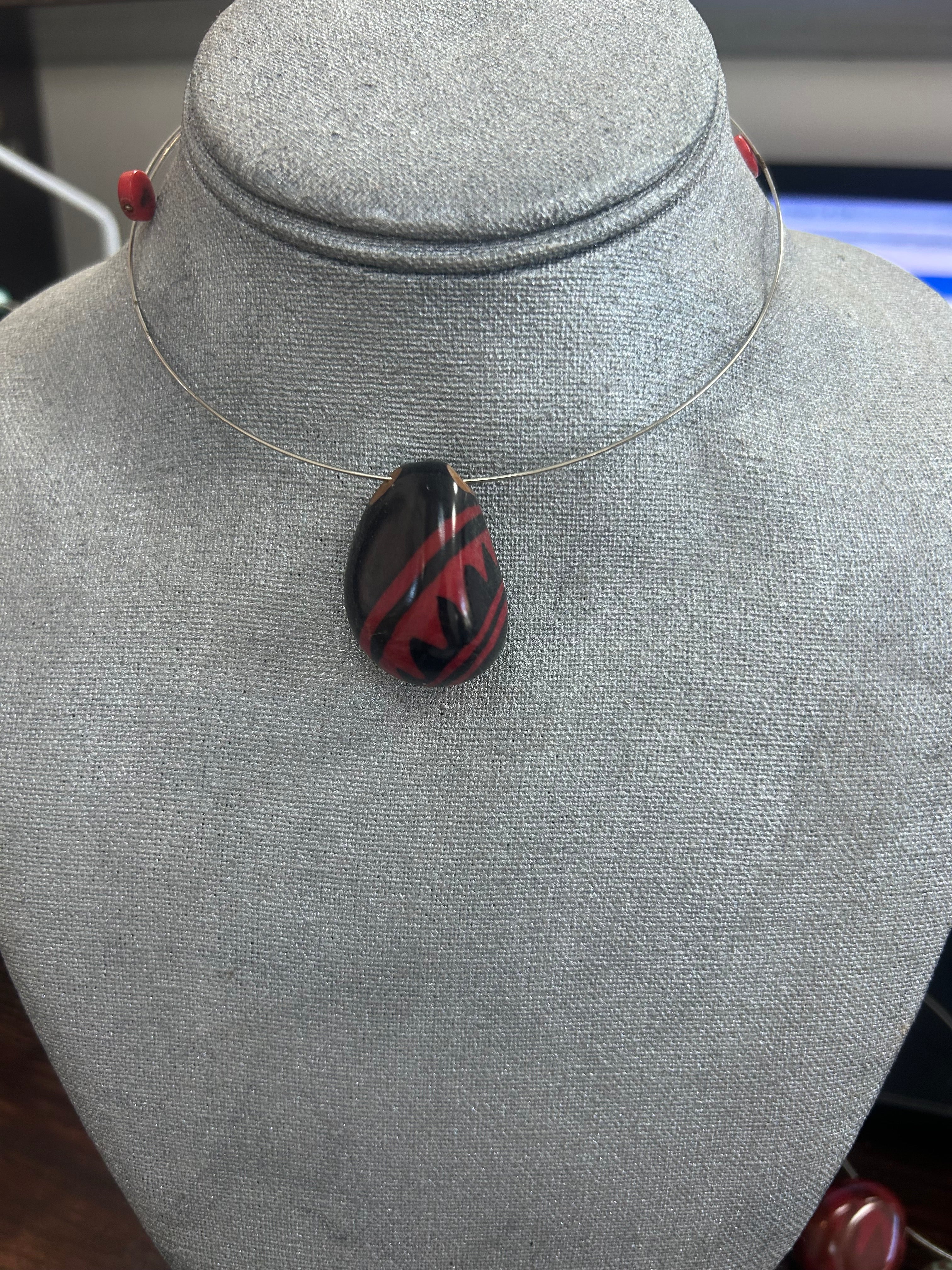 Collar con dije de piedra pulida en negro brillante, con diseño dinámico en rojo intenso