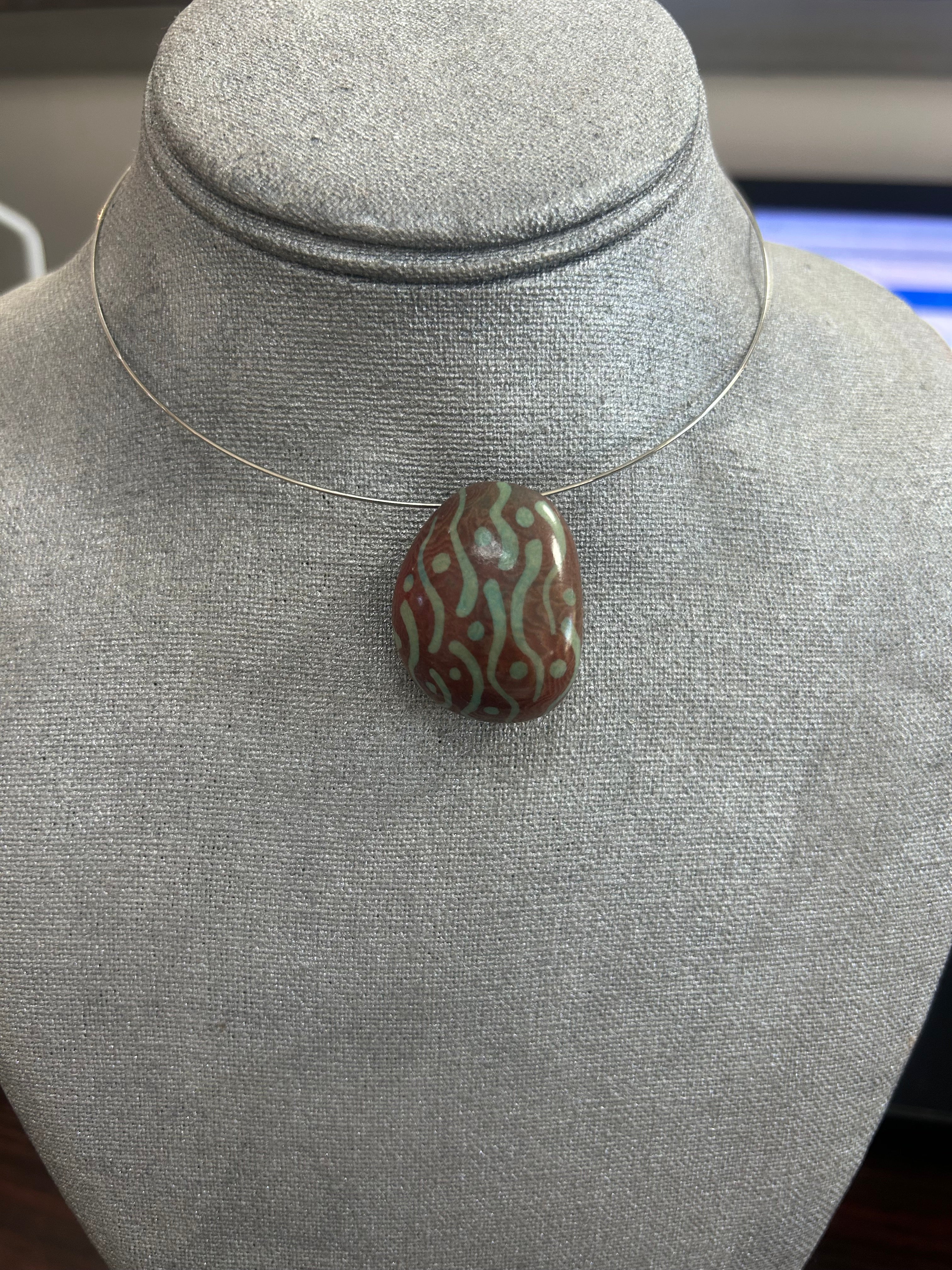 Collar con dije de piedra pulida en tono terracota, decorado con líneas y puntos en verde suave