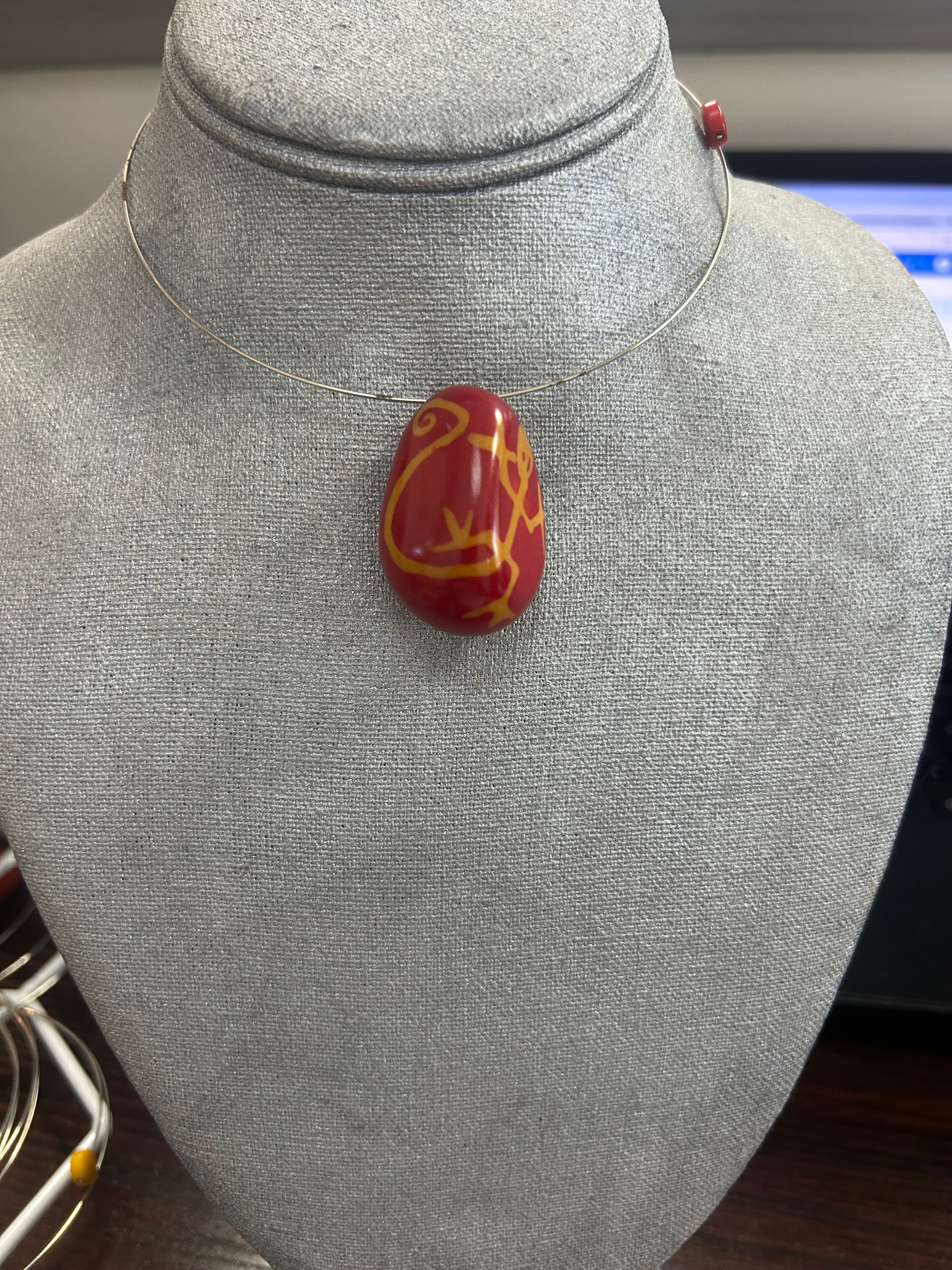 Collar con dije de piedra pulida en rojo vibrante, con delicados trazos en amarillo