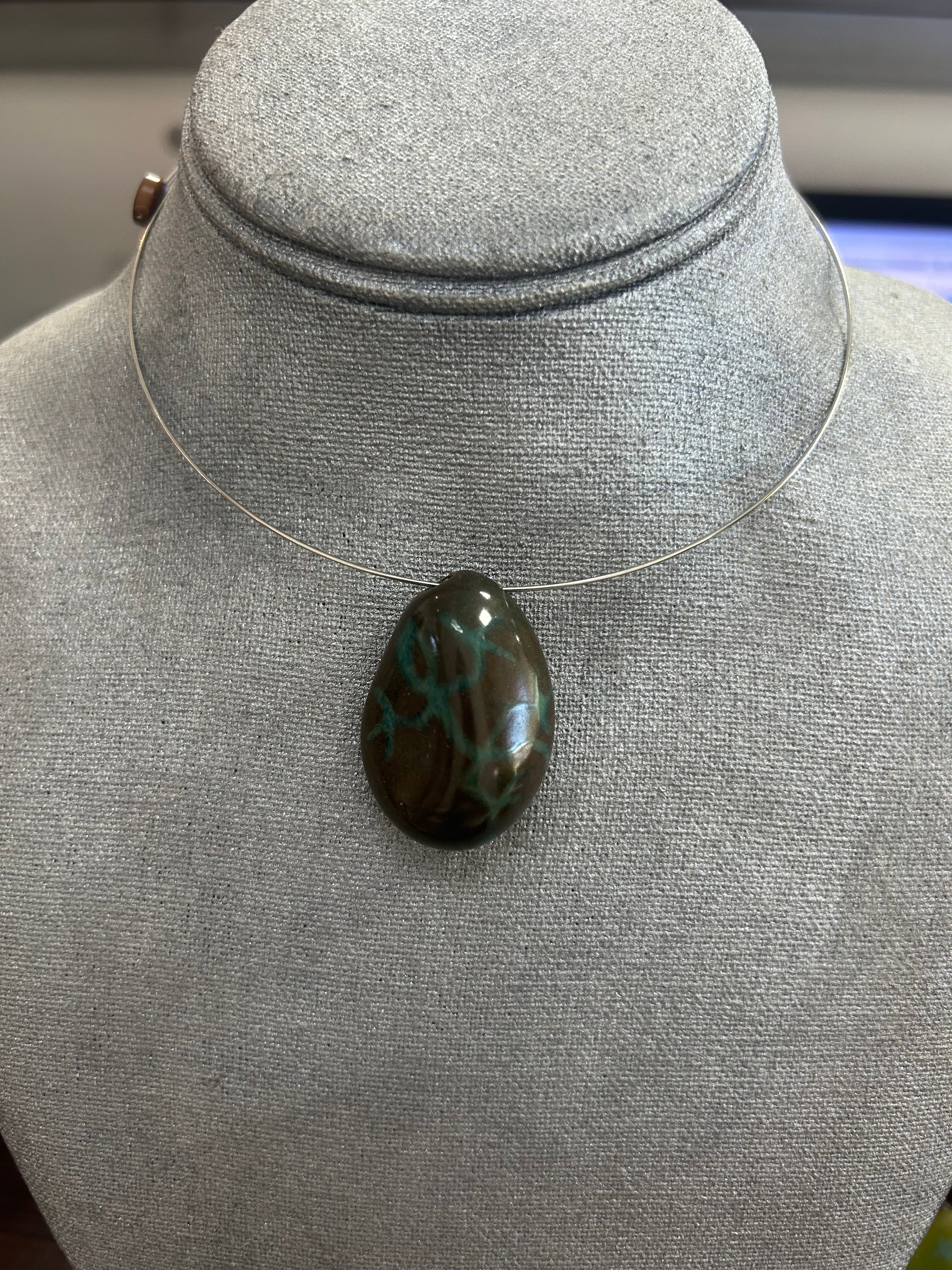 Collar con dije de piedra pulida en tono marrón profundo con vetas y detalles en verde esmeralda