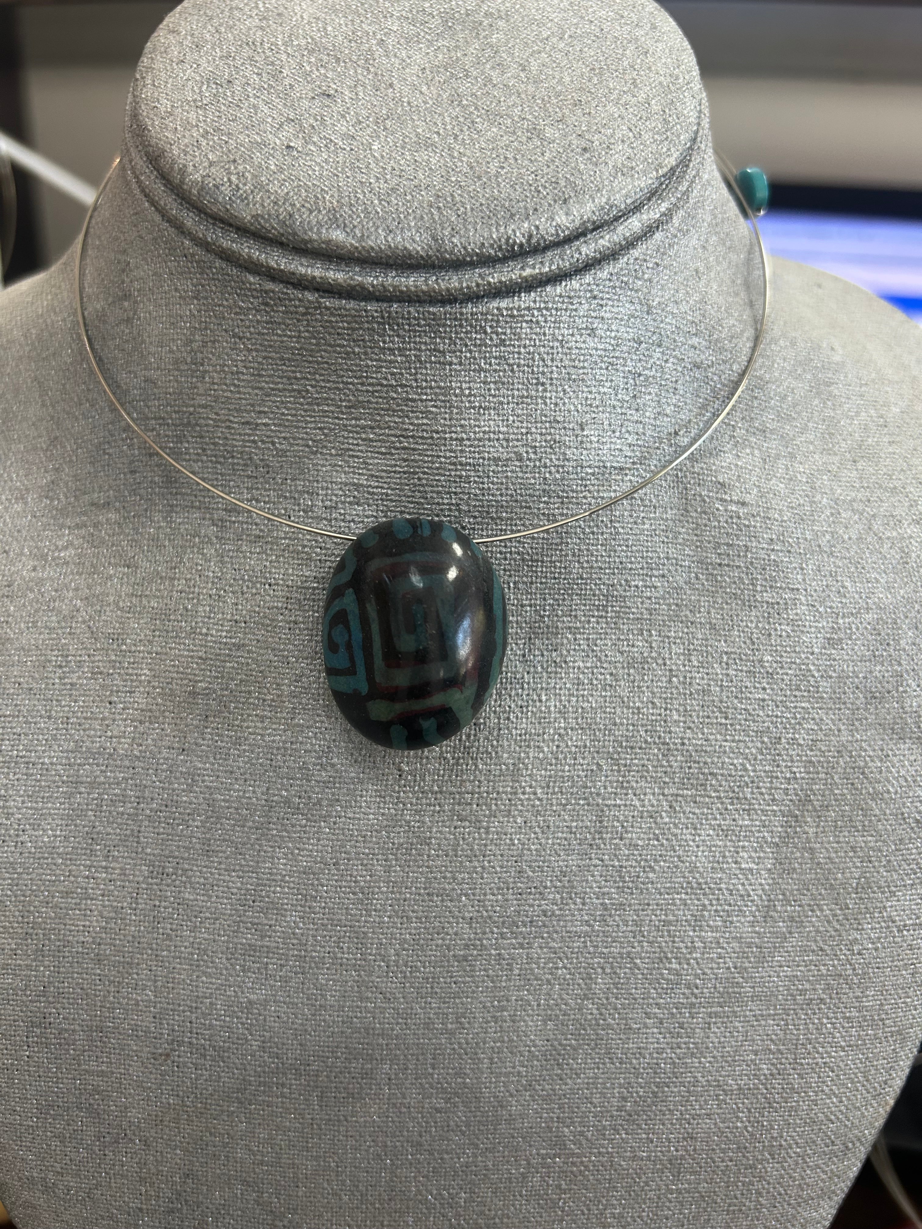 Collar con dije de piedra pulida en tono negro profundo con detalles geométricos en verde
